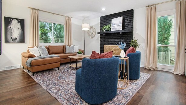 Una sala moderna con un sofá marrón, un sillón azul y una alfombra estampada.