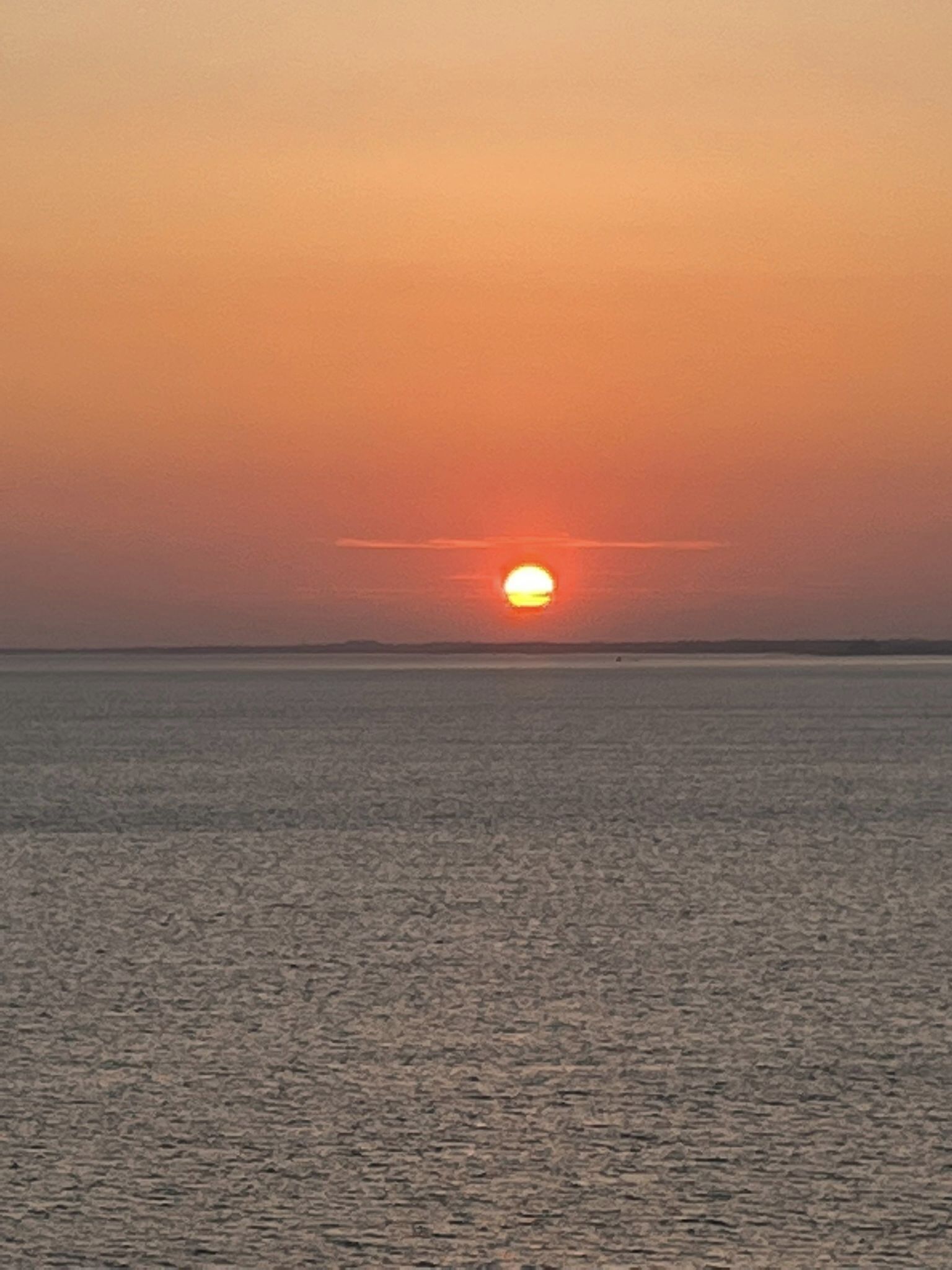 A sunset over a calm body of water with a clear horizon.
