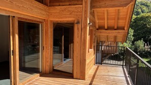 Une terrasse en bois avec une porte vitrée donnant sur un espace intérieur.