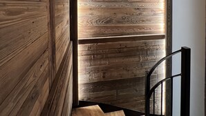Un escalier en bois au design moderne, menant à une pièce dotée d’un plafond en pente et d’une grande fenêtre.