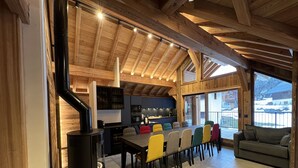 Une cuisine moderne dotée d’un grand îlot central, d’un coin repas avec des chaises colorées et d’un espace salon confortable avec un canapé.