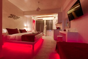 Una habitación de hotel moderna con cama, escritorio, espejo y televisión.