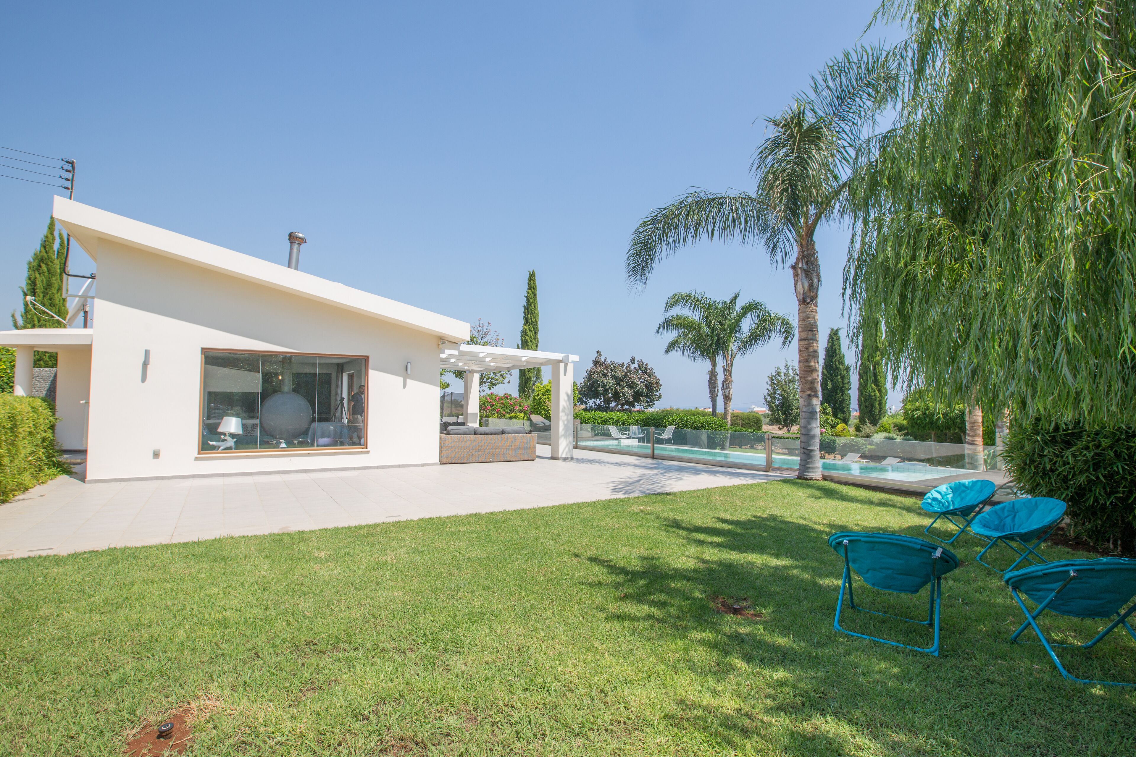 Ein modernes Haus mit Swimmingpool, einer Terrasse mit Stühlen und einem gepflegten Rasen.