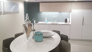 A modern dining area with a round table, chairs, and a kitchen in the background.
