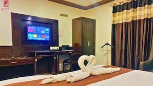 Een hotelkamer met een bed, een televisie, een bureau en een kledingkast.
