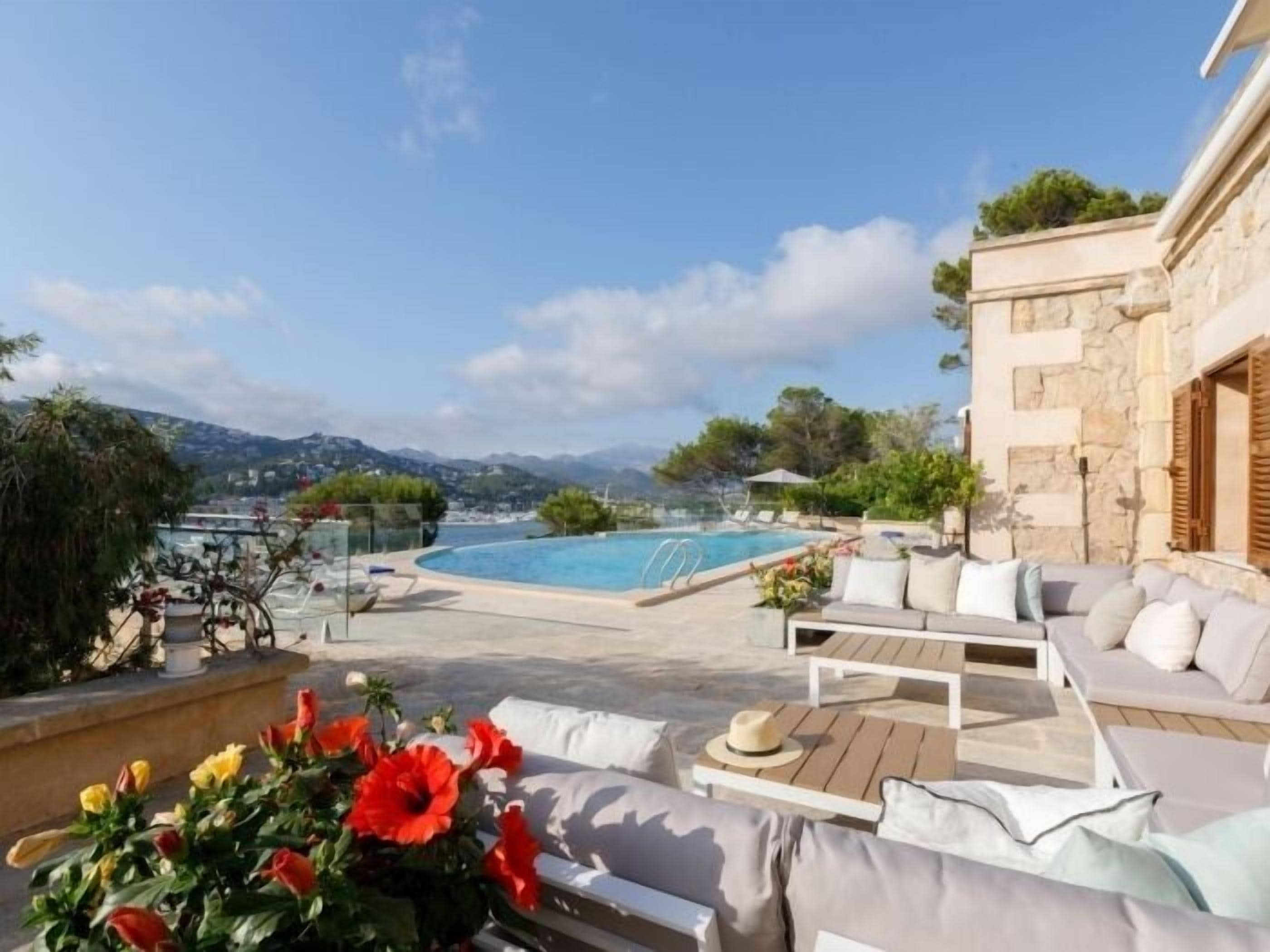 A poolside area with a view of mountains, a stone building, and outdoor seating.