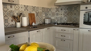 A modern kitchen with a white countertop, a bowl of lemons, and a patterned backsplash. - Casa D'ambrosio vacation Breathtaking views (Camerota)