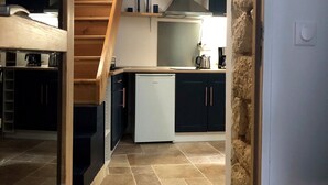 A kitchen with a dishwasher, a stove, and a sink. There is a wooden staircase leading to an upper level. - A 2 pas du Panthéon en Plein Cœur du Quartier Latin (Paris)