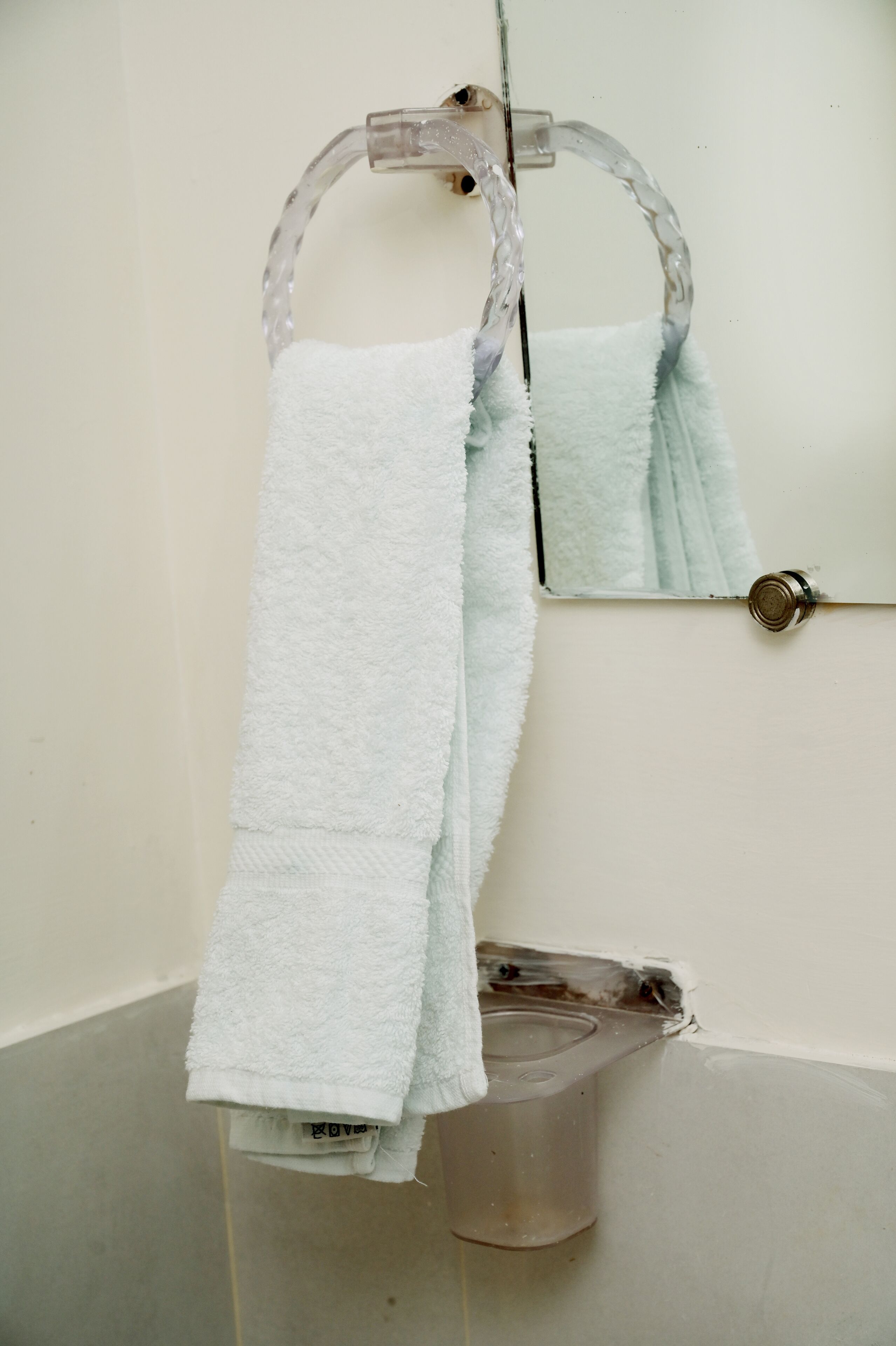 Un baño con una bañera blanca, un perchero con una toalla blanca y un espejo.