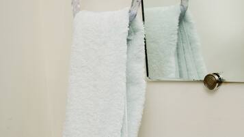 Un baño con una bañera blanca, un perchero con una toalla blanca y un espejo.