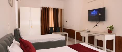 A hotel room with a bed, a desk, a chair, a TV, and a ceiling fan.