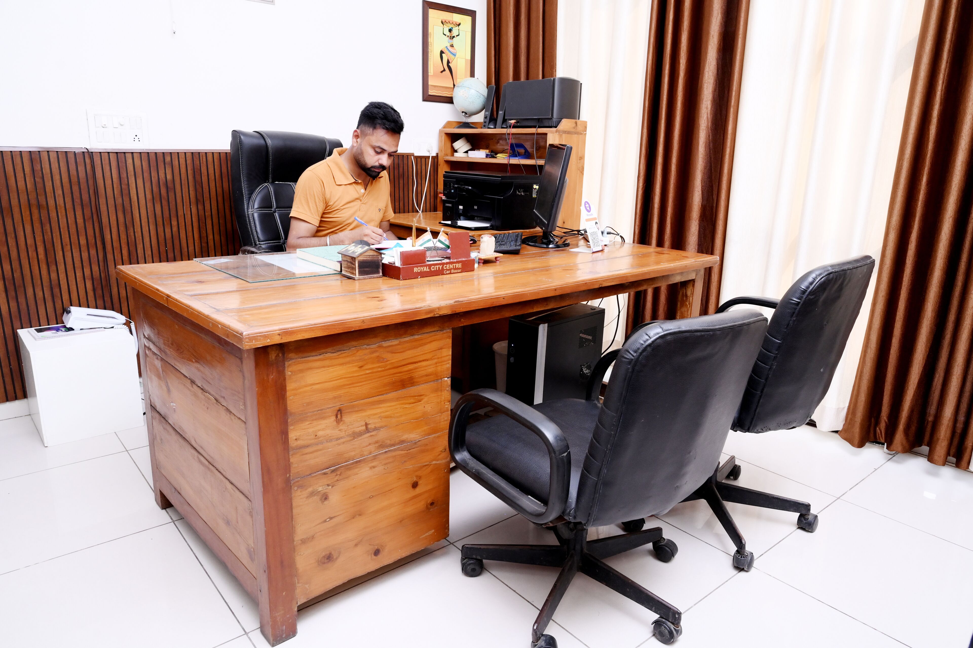 A wooden desk with a computer, a chair, and a small cabinet.