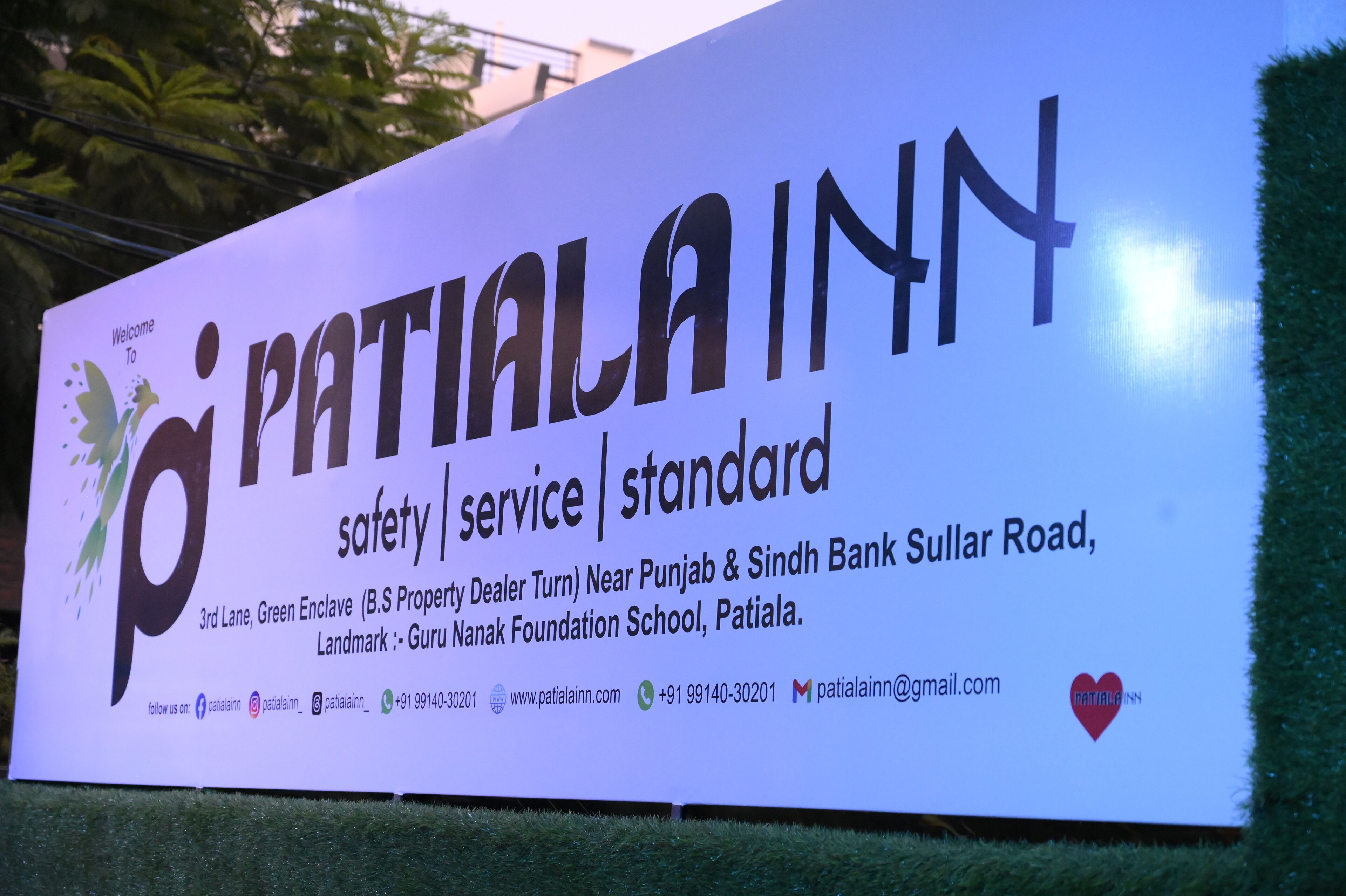 A signboard for Patiala Inn with the text 'Patiala Inn' prominently displayed, along with contact information and location details.