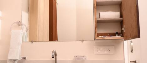 A bathroom with a white sink, a mirror, and a wooden cabinet with towels.