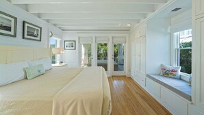 Une chambre avec un grand lit, un coin fenêtre agrémenté de coussins et une vue sur l’extérieur.