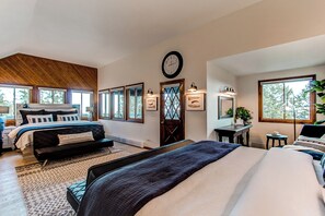 Un dormitorio amplio con una cama grande, un sofá más pequeño y una zona de escritorio.