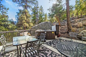 Une terrasse extérieure avec un jacuzzi, des sièges et une vue sur la forêt.
