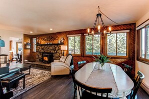 Una sala de estar acogedora con chimenea, un comedor con una mesa grande y una pared de piedra.