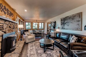 A cozy living room with a stone fireplace, leather sofa, and a large painting on the wall. - Morrison Retreat ~ 15 Min To Red Rocks Amphitheatre ~ Hot Tub, Game Room, Views (Morrison)