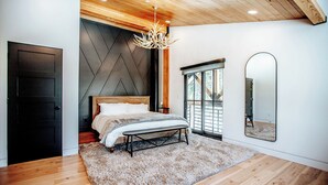 Un dormitorio con cama, candelabro, un espejo grande y vistas al exterior.