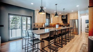 Una cocina moderna con una isla grande, luces colgantes y muebles de madera.