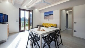 Un comedor moderno con una mesa blanca, sillas negras, un banco amarillo estampado y un ventilador de techo.