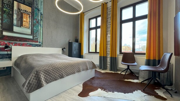 Une chambre moderne avec un grand lit, un bureau, une chaise et un tapis en peau de vache.