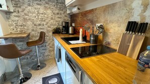 Une cuisine moderne avec un plan de travail en bois, des appareils en acier inoxydable et des tabourets de bar.