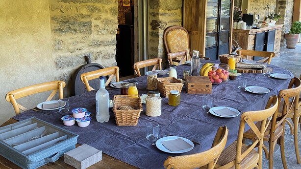 A rustic dining area with a long table set for a meal, surrounded by wooden chairs. - Chambres et Table D'hôte au Cœur de la Castagniccia Dans une Bâtisse du Xviii S (Verdèse)