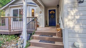 A wooden house with a blue door, a porch with steps, and a small statue on the steps. - Buttercup Haven at Pine Mountain Lake (Groveland)
