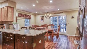 A spacious kitchen with wooden cabinets, a granite countertop, and a dining area with wooden chairs. - Buttercup Haven at Pine Mountain Lake (Groveland)
