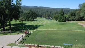 A golf course with a well-maintained fairway, trees, and a distant building. - Buttercup Haven at Pine Mountain Lake (Groveland)