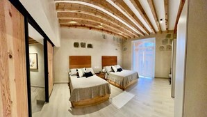 Ein modernes Schlafzimmer mit zwei Betten, Holzbalken an der Decke und einem großen Fenster.