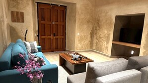 Ein modernes Wohnzimmer mit einer Couch, einem Sessel, einem Couchtisch und einem an der Wand befestigten Fernseher.