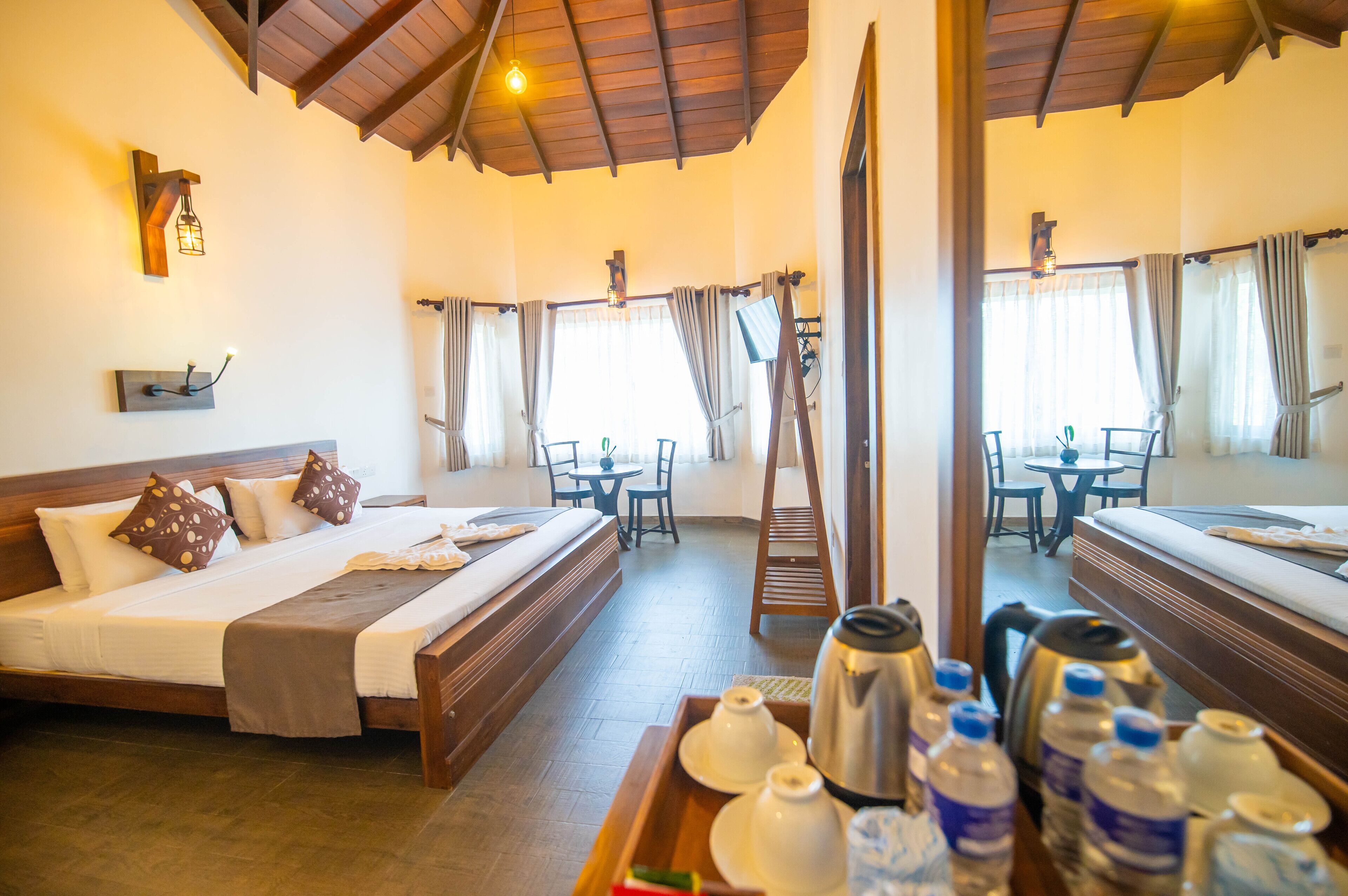 Habitación de hotel con una cama grande, techo de madera, una mesa de comedor con sillas y una escalera.
