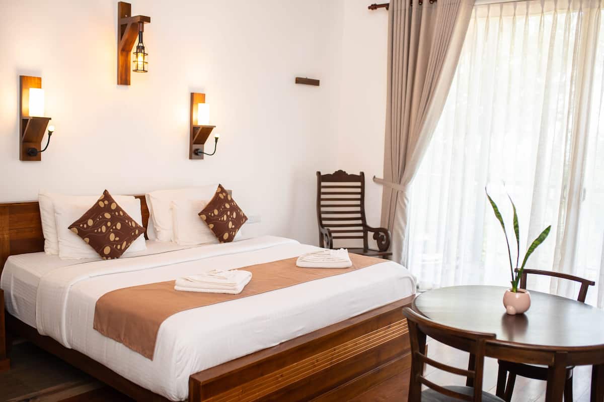 A neatly made bed with white linens and brown accents, a wooden headboard, and a bedside table with a potted plant.