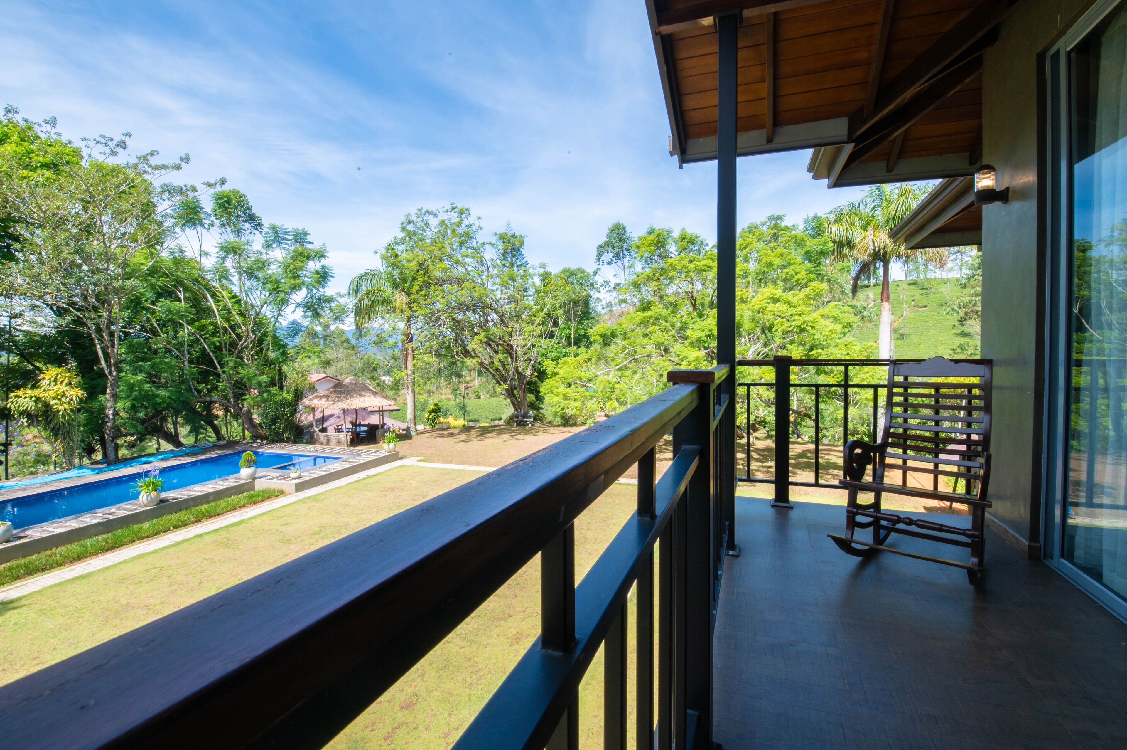 Ein Balkon mit Blick auf einen Swimmingpool und üppiges Grün.