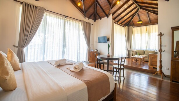 A hotel room with a large bed, wooden ceiling, and a dining area with a table and chairs. - Grand Argyle Resort & Villas (Hatton)