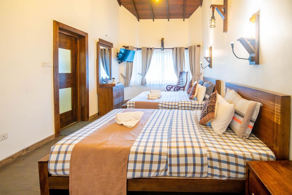 A hotel room with two beds, a wooden headboard, a flat-screen TV, and a ceiling fan.