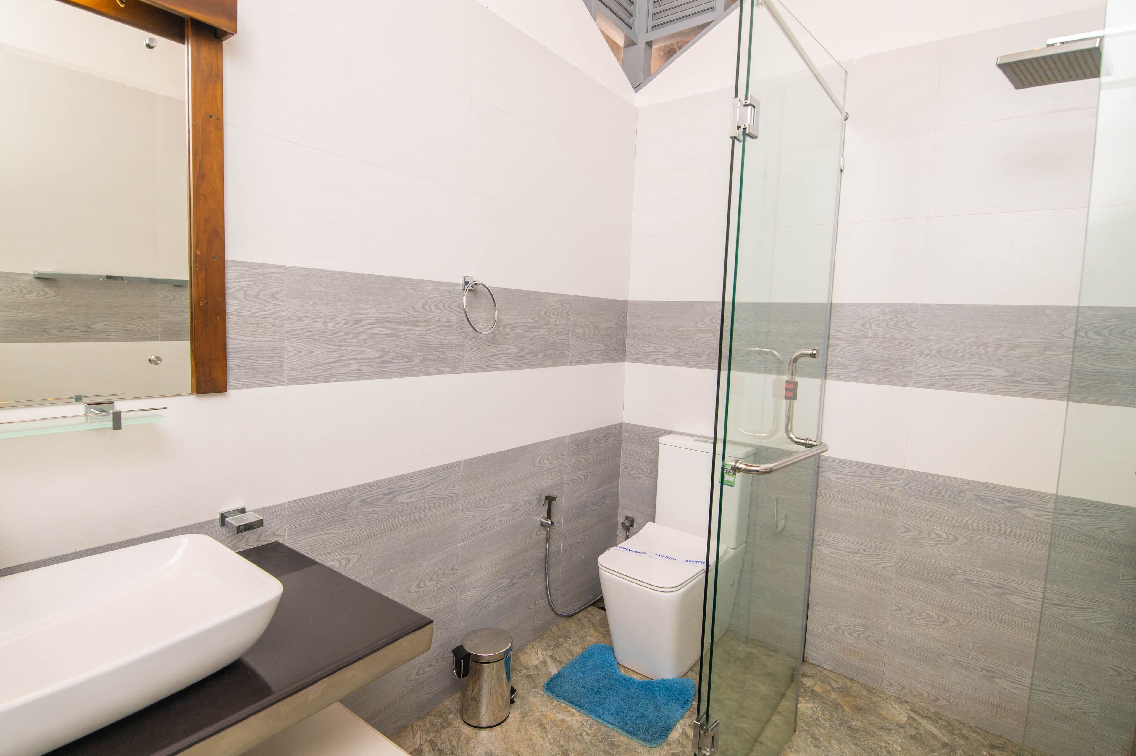 A modern bathroom with a glass shower enclosure, a white toilet, and a sink with a dark countertop.