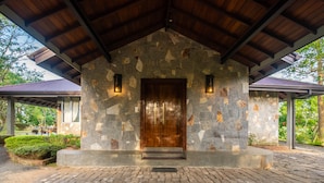 A stone building with a wooden door and steps leading up to it, surrounded by a brick-paved area and greenery. - Grand Argyle Resort & Villas (Hatton)