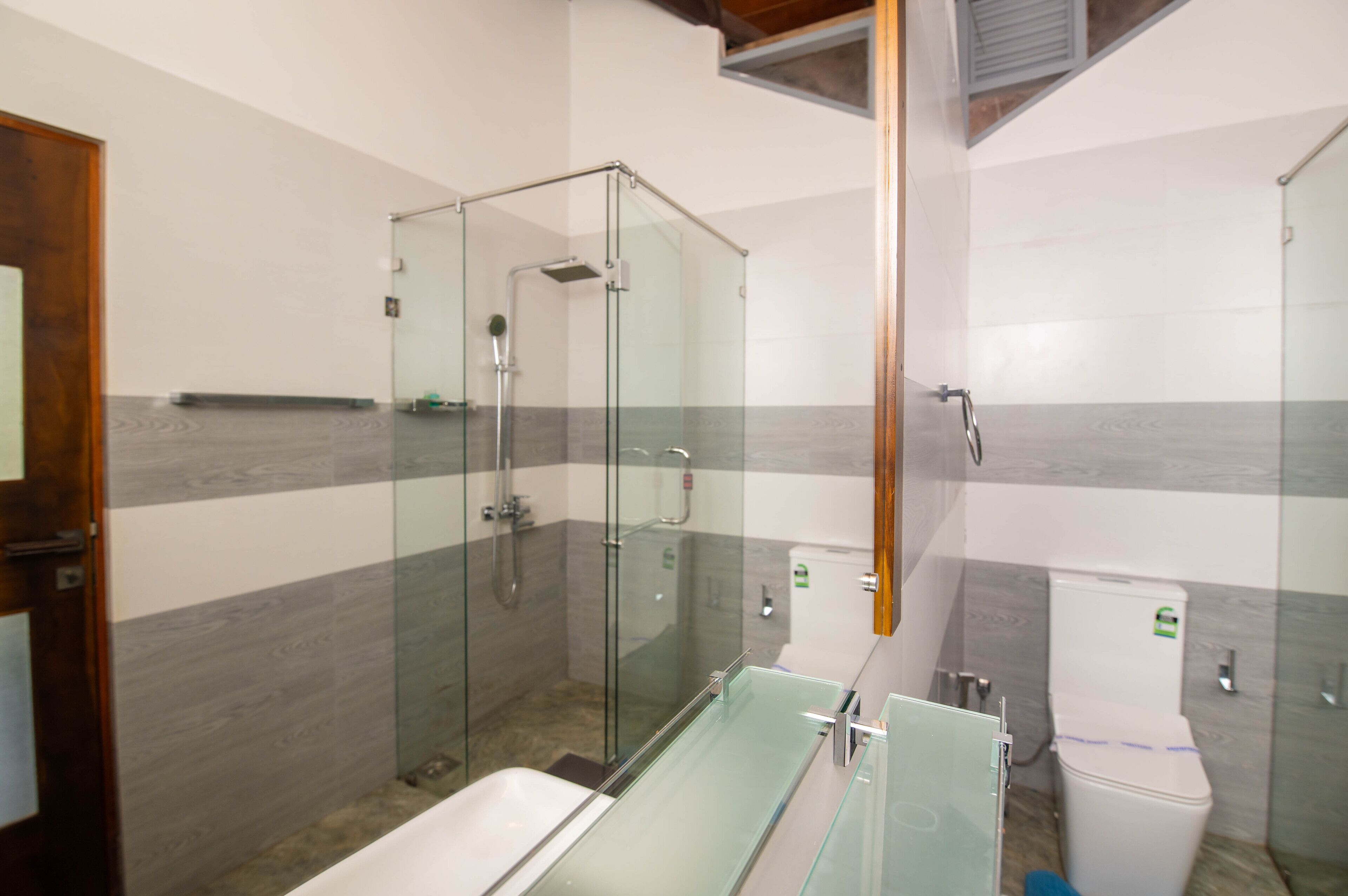 Un baño moderno con ducha acristalada, bañera de vidrio y un inodoro.