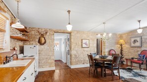 A rustic kitchen with wooden countertops, a stone wall, and a mounted deer head. - Newly Renovated | 2BR | Hot Tub | Walk to Downtown (Fredericksburg)