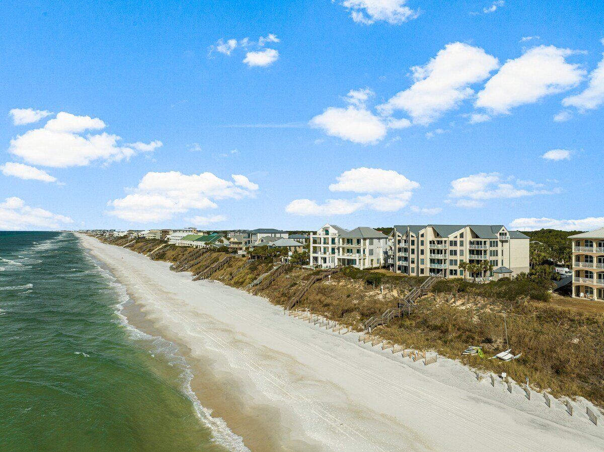 A beachside hotel with a long beachfront, multiple buildings, and a clear sky.