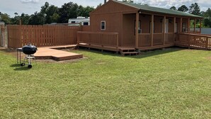 A wooden deck with a barbecue grill, a covered porch, and a fenced yard. - Quiet Cabin with Owa theme park, shopping, dining and the beach minutes away.  (Elberta)