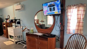A room with a wooden dresser, a mirror, a television, and a chair. - Quiet Cabin with Owa theme park, shopping, dining and the beach minutes away.  (Elberta)