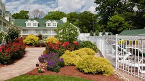 A two-story building with a green roof and a garden with various colorful flowers and shrubs.