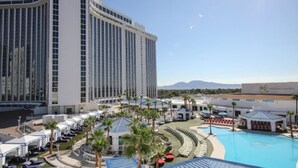 A resort with a large pool, palm trees, and a view of mountains.