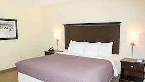 A hotel room with a large bed, two bedside tables, a nightstand, and a framed picture on the wall. - ADA Glacier Suite at Kelley's Island Venture Resort (Kelleys Island)