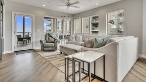 A spacious living room with a large window, a ceiling fan, and a view of the outside.